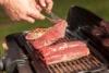 Entrecote : A man turns a steak on a electric grill Stock Photo