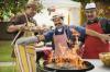 Hispanic men leaning back from fire in barbecue grill